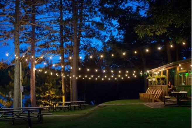 Pitlik's Resort exterior with fairy lights and picnic tables.