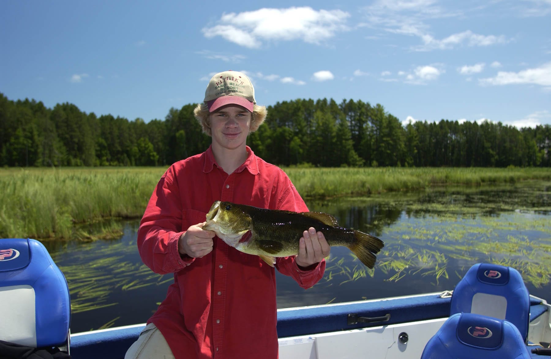 Young man on lake holding a bass.